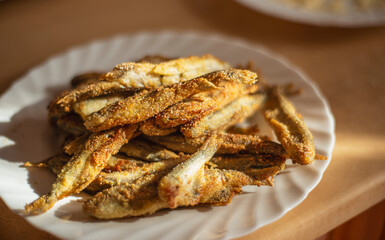 fried capelin on a white plate, small fish in corn breading on a white plate, simple homemade food concept, home cooking fish cooking