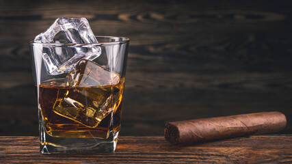 Whiskey and cigar. Glass of whiskey, Bourbon or Brandy with ice cube and cigars from Cuba Havana on...