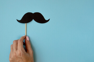 Happy father day, retro black photo booth props mustache on stick in female hand on blue background...