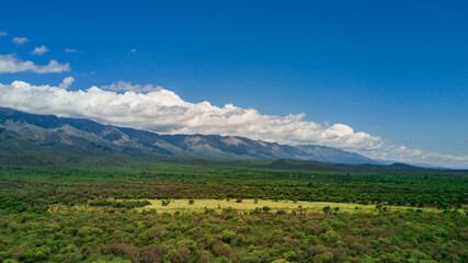 Naklejka premium Las montañas mas altas, con las nubes pasando sobre ellas y el camino bordeando la base de la montaña hasta el horizonte. Cerro Champaqui. Merlo. Córdoba. Argentina