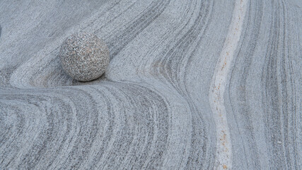Close up of one round stone on grey granite  stone waves made by crystal clear water. Spa and...