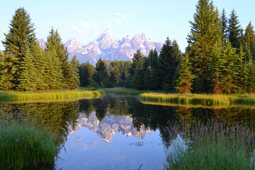 The Grand Teton peaks rise above a still lake