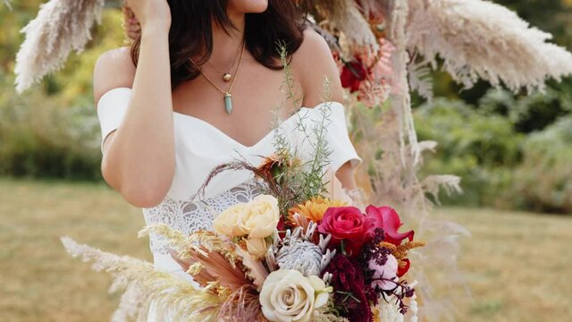 Bride in wedding gown with bouquet poses in wide brim fedora laughing, Tilt Up