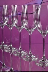 Diagonal of five empty wine glasses on a colored abstract background and reflective surface