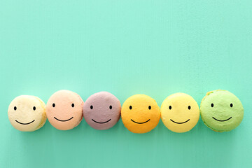 colorful macaron or macaroon with happy face on wooden mint background
