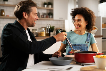 Boyfriend and girlfriend eating lunch together at home. Husband and wife enjoying in delicious food