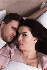High angle view of adult couple looking at camera on bed