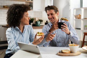 Loving couple drinking coffee and eating sandwich. Happy smiling wife enjoy in the morning with her husband