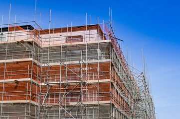 Scaffolding around the outside of a new block of flats under construction. No people.