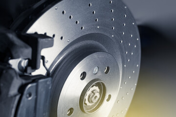 Installation of new perforated brake discs and pads on a modern auto in a car workshop. Close up. Blur effect. © ARTPROXIMO