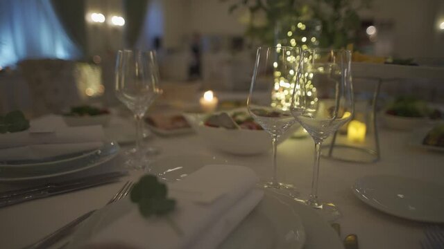 Festive table setting. Glasses and plates on a banquet table. Night Party at a fancy restaurant. Celebration event on holidays. Beautiful decoration with candles on tables. Gourmet and luxury dinner.