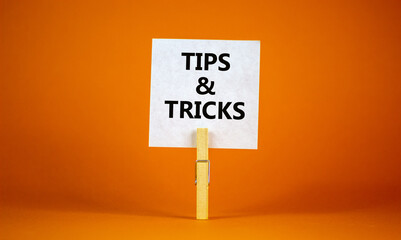 Tips and tricks symbol. White paper on wooden clothespin. Words 'Tips and tricks'. Beautiful orange...