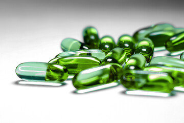 Pharmaceutical medicine colorful pills on the table, green capsules on white background