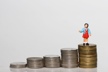 Investment planning for Kid future concept, girl doll stand on coin with white background.