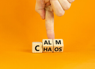Stop chaos, time to calm symbol. Businessman turns wooden cubes and changes the word 'chaos' to 'calm'. Beautiful orange background, copy space. Business and chaos or calm concept.
