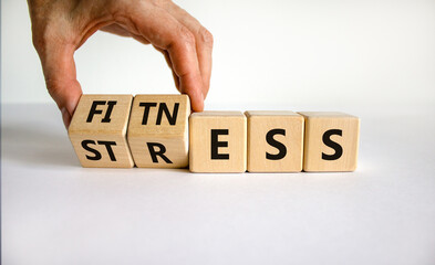 Fitness vs stress symbol. Doctor turns cubes and changes the word 'stress' to 'fitness'. Beautiful white table, white background. Medical, psychological, fitness vs stress concept. Copy space.