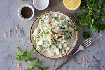 Delicious shrimp salad with vegetables and sour cream on a white plate. Top view