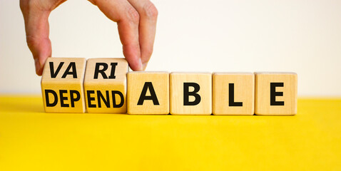 Dependable or variable symbol. Businessman turns wooden cubes and changes the word dependable to...