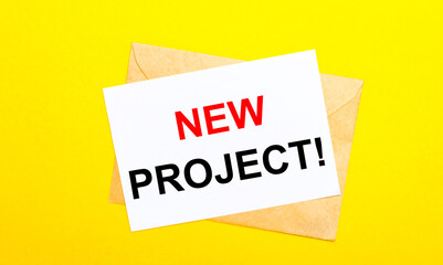 On a yellow background, an envelope and a card with the text NEW PROJECT. View from above