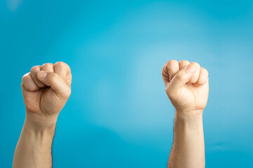 Male fists, isolated on a blue background. Close fists symbolizing the resistance movement in the world.