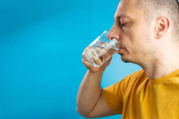 Man drinking water isolated in studio. A man drinks water from a glass. handsome man wearing glasses and shirt. Standing drinking glass of healthy water to refreshment over isolated white background