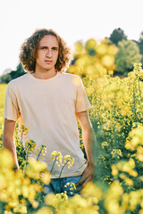a young man surrounded with yellow flowers in a sunny spring day