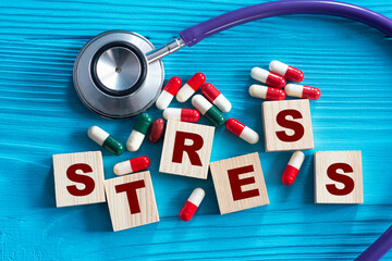 STRESS - word on wooden cubes on a blue background with a stethoscope
