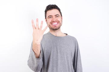 young handsome caucasian bearded man wearing pyjama over white wall smiling and looking friendly, showing number four or fourth with hand forward, counting down