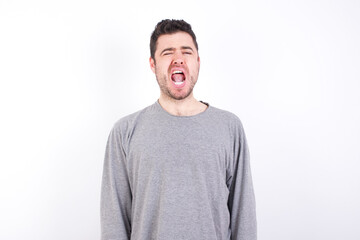 Obraz premium young handsome caucasian bearded man wearing pyjama over white wall yawns with opened mouth stands. Daily morning routine