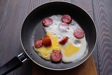 fried egg with sausage in a frying pan on a wooden table