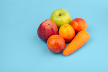 Vegetables and fruits. Apples, carrots and red orange on a blue background with place for text. Healthy food. Diet
