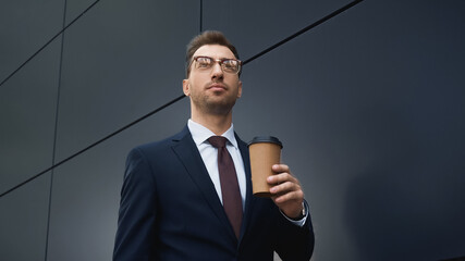businessman in formal wear holding coffee to go outside.