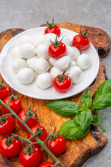 Italian tricolore, small balls of fresh white soft Italian mozzarella cheese, ripe red cherry tomatoes and fresh green basil herb, ready for making caprese salad