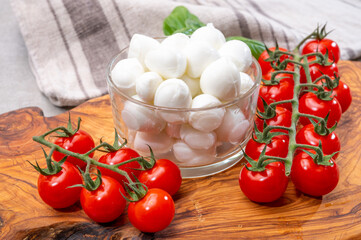 Italian tricolore, small balls of fresh white soft Italian mozzarella cheese, ripe red cherry tomatoes and fresh green basil herb, ready for making caprese salad