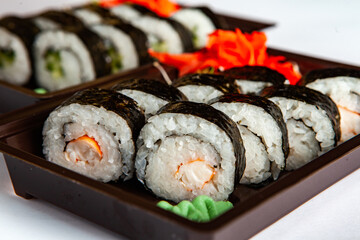 Japanese food rolls in plastic box. Sushi set in a plastic package close up isolated on a white background. Sushi for take away or sushi delivery.