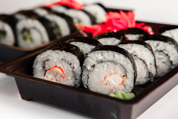 Japanese food rolls in plastic box. Sushi set in a plastic package close up isolated on a white background. Sushi for take away or sushi delivery.