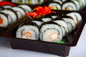 Japanese food rolls in plastic box. Sushi set in a plastic package close up isolated on a white background. Sushi for take away or sushi delivery.