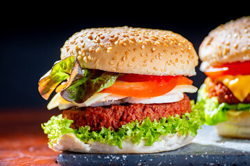 Tasty vegetarian food, homemade cheeseburgers made from plant based soya meat with cheese, onion, green lettuce and tomatoes