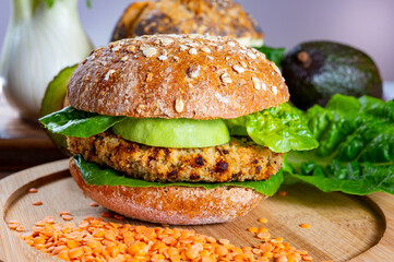 Tasty vegetarian healthy food, homemade burgers made from orange lentils legumes with green lettuce and fresh ripe avocado