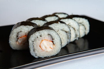 Japanese food rolls in plastic box. Sushi set in a plastic package close up isolated on a white background. Sushi for take away or sushi delivery.