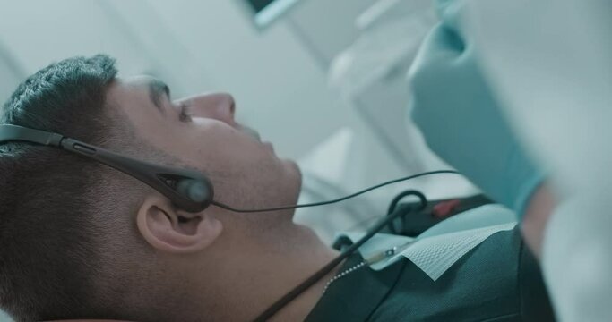 An Arabian male patient is having a Joint vibration analysis procedure (JVA) and laying in the dental chair.