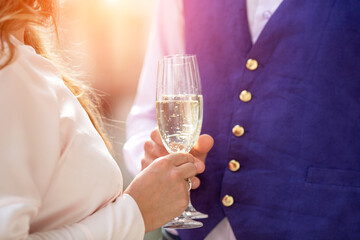 Close-up of glasses of champagne in the hands of a man and a woman. Bride and groom, wedding ceremony.