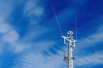 Mast of a sea vessel with navigation equipment on a background of blue sky. Cruise