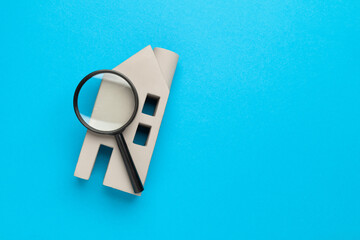 Home appraisal. House model and magnifier on a blue background. Search for a rental home while traveling.