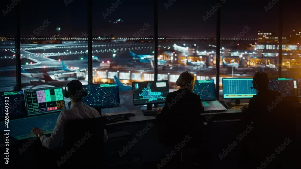 Wall mural diverse air traffic control team working in a modern airport tower at night. office room is full of 