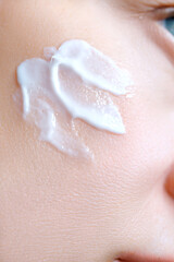 Cosmetic cream on the skin of a woman's face close-up