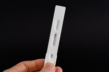 Holding a Covid-19 antigen saliva test with negative result. Plastic specimen for a rapid...