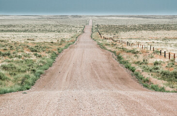 Deserted road and fences stretching out to the horizon, late afternoon, Weld County, Colorado