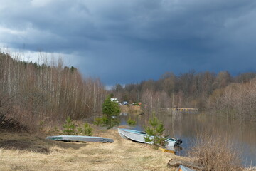 Naklejka premium River bank, spring, day, blue sky. There are boats on the shore.