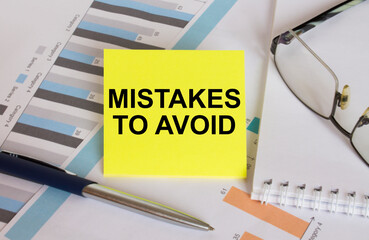 Yellow sticker with text Mistakes To Avoid lies on financial charts with pen and eyeglass